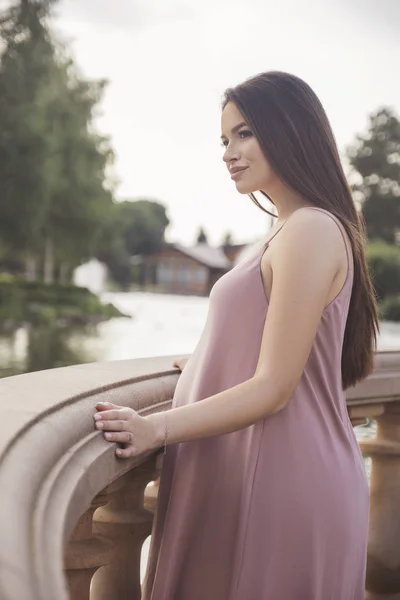 Sexy brünette schwangere Frau im Park. Sommertag, Sonnenuntergang — Stockfoto