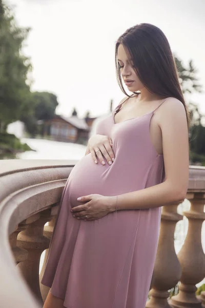 Sexy brünette schwangere Frau im Park. Sommertag, Sonnenuntergang — Stockfoto