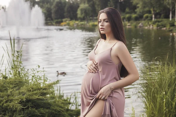 Sexy brünette schwangere Frau im Park. Sommertag, Sonnenuntergang — Stockfoto