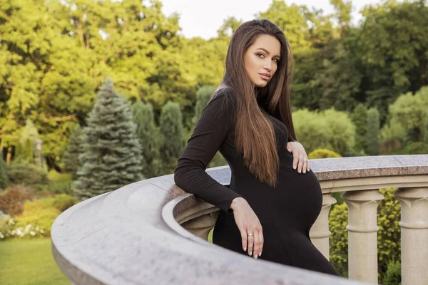 Sexy brünette schwangere Frau im Park. Sommertag, Sonnenuntergang — Stockfoto