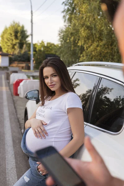 セクシーなブルネットの妊婦が車を運転した。夏の日日没 — ストック写真