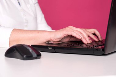 Yaşlı bir kadının fare ve dizüstü bilgisayar klavyesini eline alıp kapatmasını bekleyin. Bilgisayar oyunları oynuyor ya da internette arama yapıyor, sosyal medya sitelerinde sohbet ediyor. Beyaz masa ve pembe arkaplan