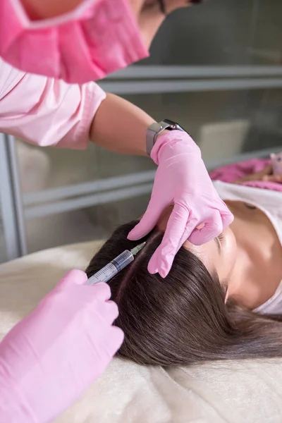 美容师医生为一位在诊所的妇女做注射手术 她戴着粉色的光泽和面具 拿着注射器和针头 — 图库照片