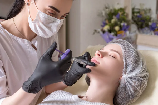 전문의는 진료소에 여성에게 주사를 시술을 마스크를 바늘로 주사기를 있습니다 — 스톡 사진
