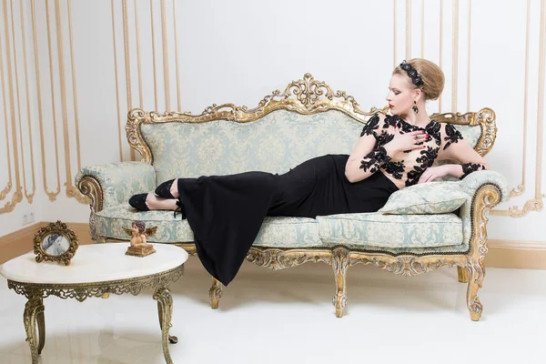 美丽的金发王妃躺在一个复古的沙发上 穿着华丽华丽的奢侈品 复制空间 — 图库照片