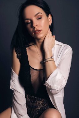 Tarafsız bir zeminde seksi giyinmiş esmer, zayıf bir kadın. Baştan çıkarıcı pozlarda stüdyo portresi.
