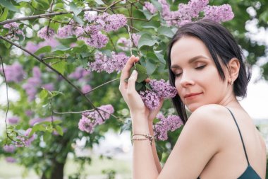 Parkta seksi elbiseli esmer kadın. Etrafı çiçeklerle çevrili. Kopya alanı ile şehvetli, yumuşak portre.