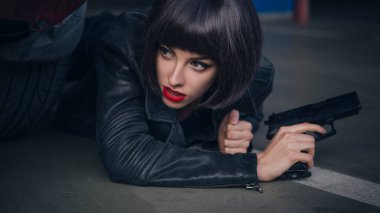 Güzel esmer, seksi ajan (katil ya da polis) Deri ceketli ve kot pantolonlu bir kadın, birinin peşinden koşuyor, onu park yerinde yakalamak için..