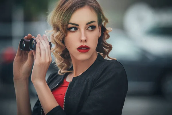 在欧洲城市 漂亮的黑发性感间谍女特工 杀手或警察 身穿皮夹克 身穿红色豪华婚纱 手里拿着冰棍在看着某个人 — 图库照片