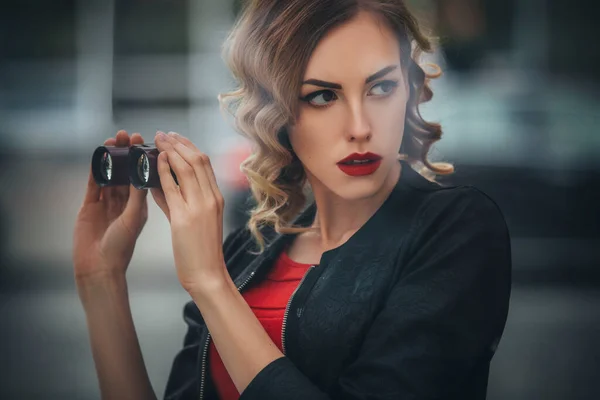 美しいブルネットセクシースパイエージェント キラーまたは警察 女性でレザージャケットと赤豪華なドレスとともに彼女の手見張りで誰か後にヨーロッパの都市 — ストック写真