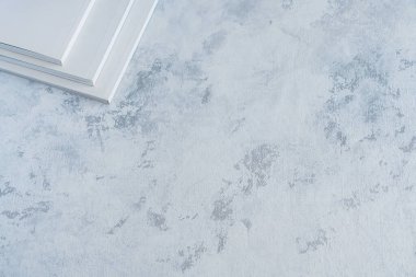 Masanın köşesinde dokulu yüzeyi olan beyaz dergiler var.