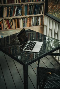 Parktaki bir kafede üzerinde kahve olan bir laptop ve bir kupa var.