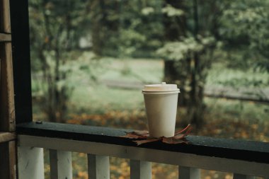 Parktaki sonbahar akçaağaç yaprağının üzerinde duran bir kupa kahve.