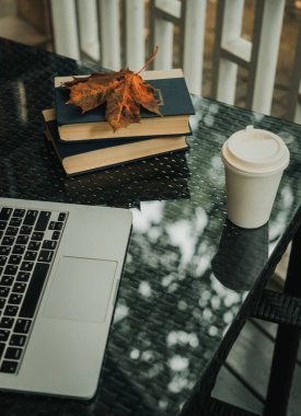 Parktaki bir kafede üzerinde kahve olan bir laptop ve bir kupa var.