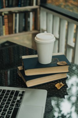 Bir kupa kahve parktaki masanın üzerindeki kitapların üzerinde duruyor.