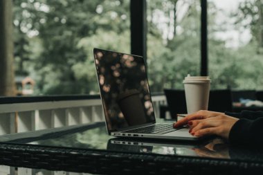 Kız bir kafede dizüstü bilgisayarın yanında oturuyor. Yakınlarda bir bardak kahve var.