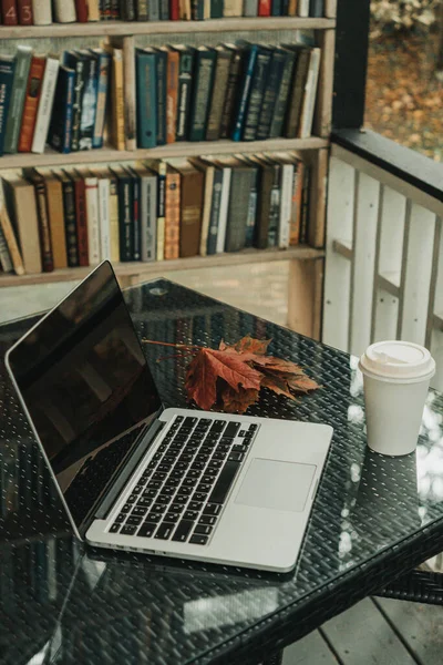 Parktaki bir kafede üzerinde kahve olan bir laptop ve bir kupa var.