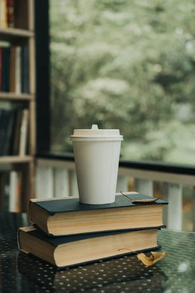 a mug of coffee stands on the books on the table in the park