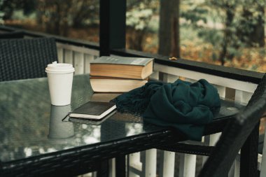 Parktaki masanın üzerinde kitaplar ve bir kupa kahve var.