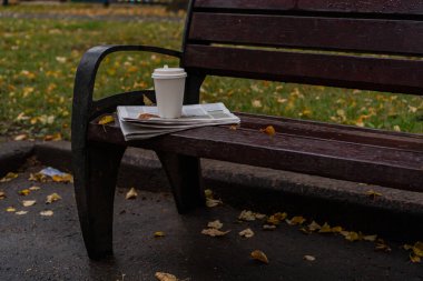 Parktaki bankta bir gazete ve bir bardak kahve var. Moskova Izmaylovsky Park, 2020 sonbaharında.
