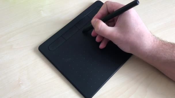 Een close-up. Mannelijke handen tekenen met een pen op een grafische tablet. Een man schrijft een e-mail met een pen op een grafische tablet. 4K. — Stockvideo