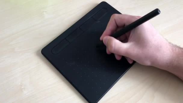 Een close-up. Mannelijke handen tekenen met een pen op een grafische tablet. Grafisch ontwerper doet werk aan de computer. Een man schrijft een e-mail met een pen op een grafische tablet. 4K. — Stockvideo