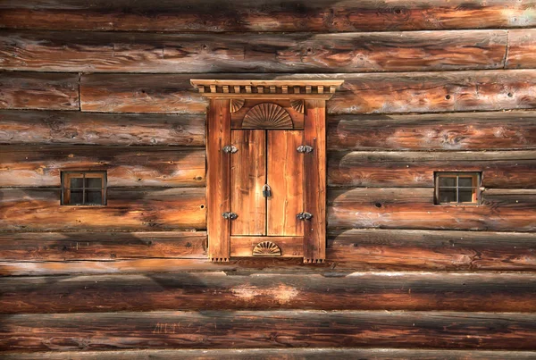 Old wooden window shutters on a log wall. Carved wooden window. Traditional Russian wood carving