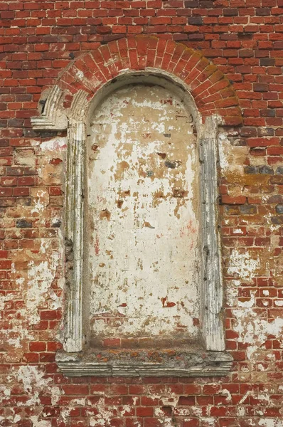Old arched window on a red brick wall of christian church