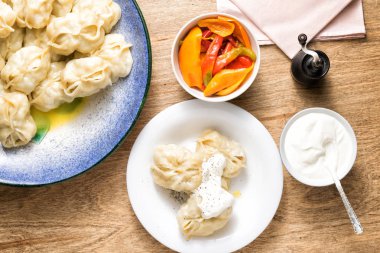 Manti büyük bir tabak üzerinde. Baharatlı krema ve biber