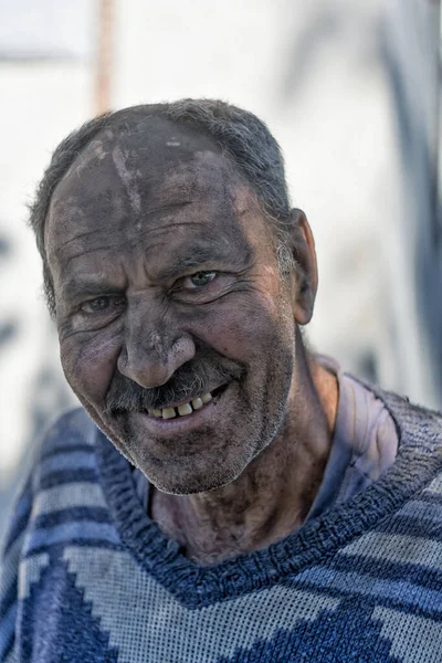 Elderly smiling man with a face in black dust — Stock Photo, Image