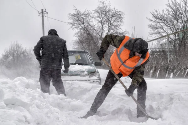 Trasporto, inverno, persone e concetto di veicolo - primo piano dell'uomo che scava neve con pala vicino all'auto — Foto Stock