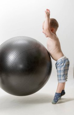 Tatlı çocuk spor olsun diye büyük bir topla oynuyor.