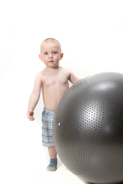 Netter Junge spielt mit einem großen Ball für Fitness — Stockfoto