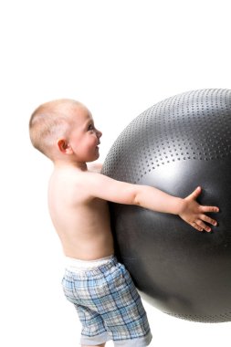 Tatlı çocuk spor olsun diye büyük bir topla oynuyor.