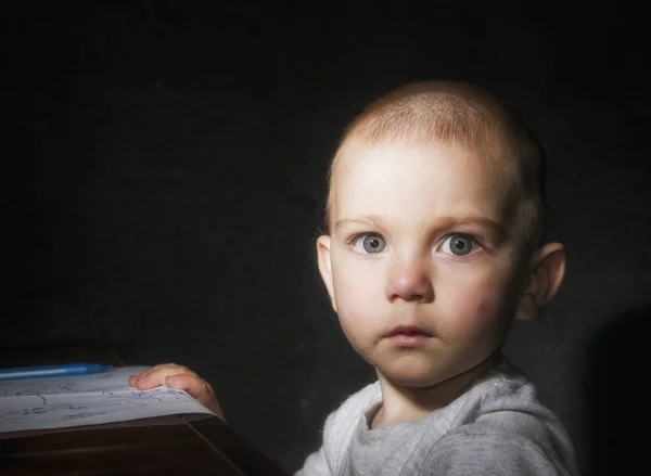 Criança loira de olhos azuis com um olhar surpreso e uma boca suja depois de comer em um fundo preto — Fotografia de Stock