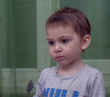 İki yaşındaki güzel bebeğin kaşıkla yemek yemesine yakın durun.