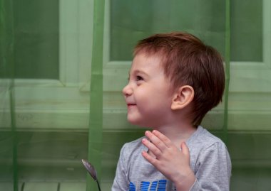 İki yaşındaki güzel bebeğin kaşıkla yemek yemesine yakın durun.