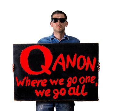 Siyah gözlüklü bir adam üzerinde kırmızı QAnon yazan siyah bir poster tutuyor. Biz nereye gidersek, hepimiz gideriz. Gölge dünyası komplosu konsepti. Beyaz arkaplanda izole et