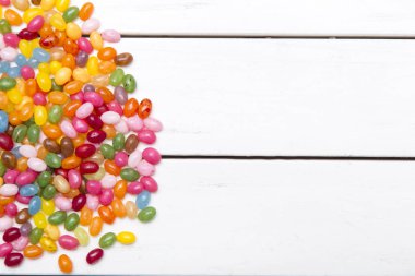 çok tatlı şekerler ile renkli arka plan üzerinde beyaz ahşap masa dağınık