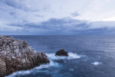 Güzel doğal sahne. Dalgalar kayalara bulutlu bir mavi gökyüzü altında kırma