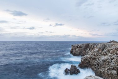 Güzel doğal sahne. Dalgalar kayalara bulutlu bir mavi gökyüzü altında kırma