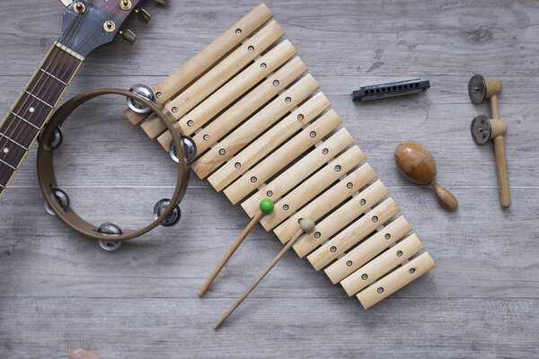 Several percussion instruments on a grey wooden table with space for text. Music class background
