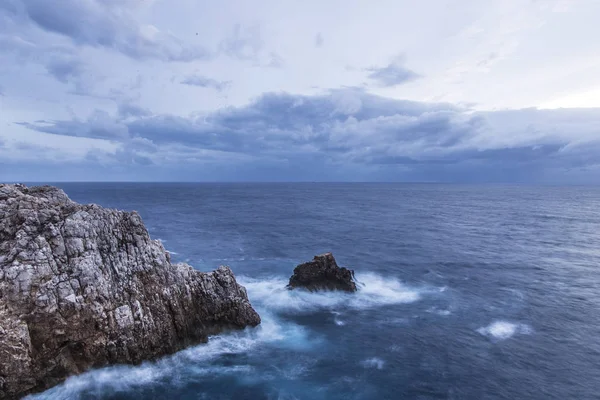Güzel doğal sahne. Dalgalar kayalara bulutlu bir mavi gökyüzü altında kırma