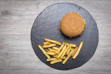 Havadan görünümü bir ev hamburguer ile kaşar peyniri, domates, marul, kişiler üzerine bir yazı tahtası üzerinde gri ahşap masa ile servis yaptım. Hipster burger