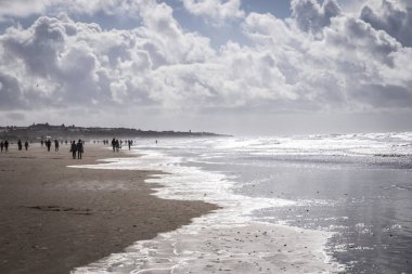 kumlu plaj güzel deniz manzarası ile insanlar ve deniz dalgalarının siluetleri 