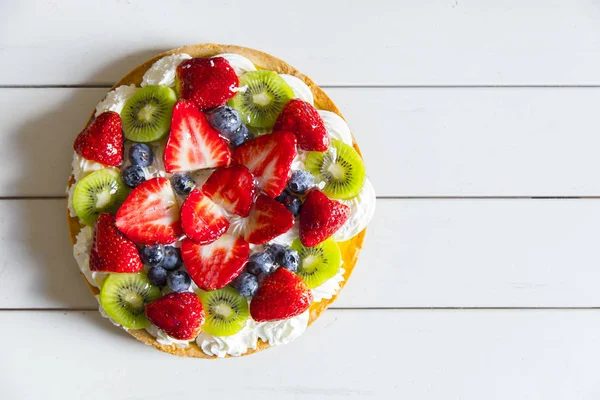 Pasta krema, çilek, yaban mersini ve kivi ile üstten görünüm Beyaz ahşap tablo