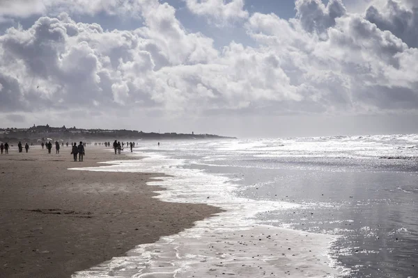 kumlu plaj güzel deniz manzarası ile insanlar ve deniz dalgalarının siluetleri 