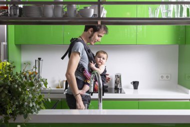 Genç Baba kahve onun bebeği ile taşıyıcıya yeşil modern mutfak