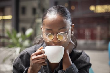 çekici genç Afrikalı kadın modern bir terasta çay sahip 