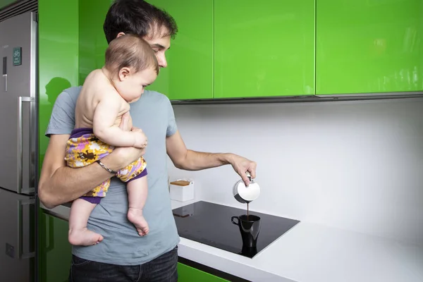 Genç Baba kahve onun bebeği ile taşıyıcıya yeşil modern mutfak